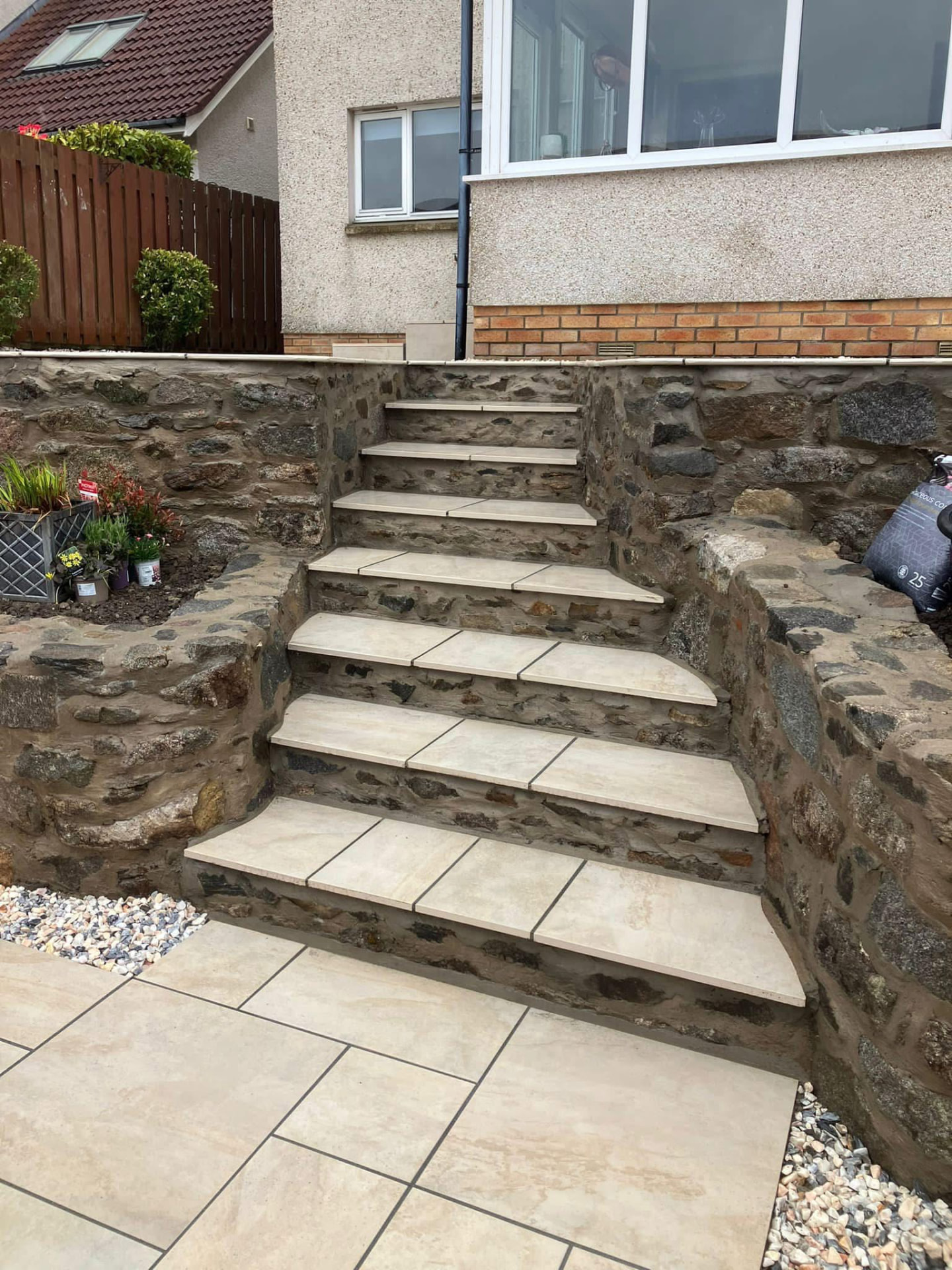 Stone steps with porcelain paving set into a rustic stone wall, built by Gillies Construction in Aberdeen